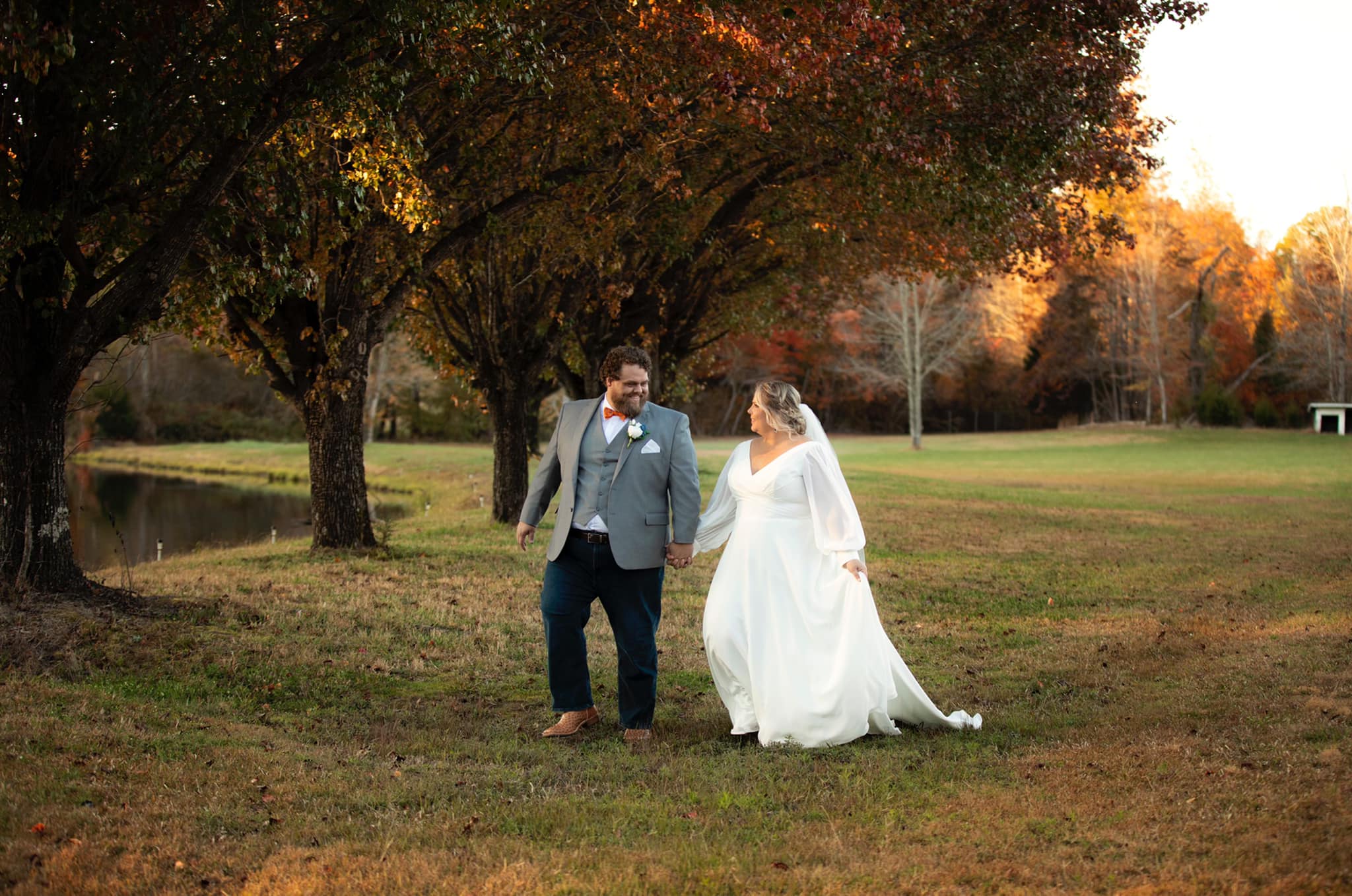 bride and groom walking alongside lake