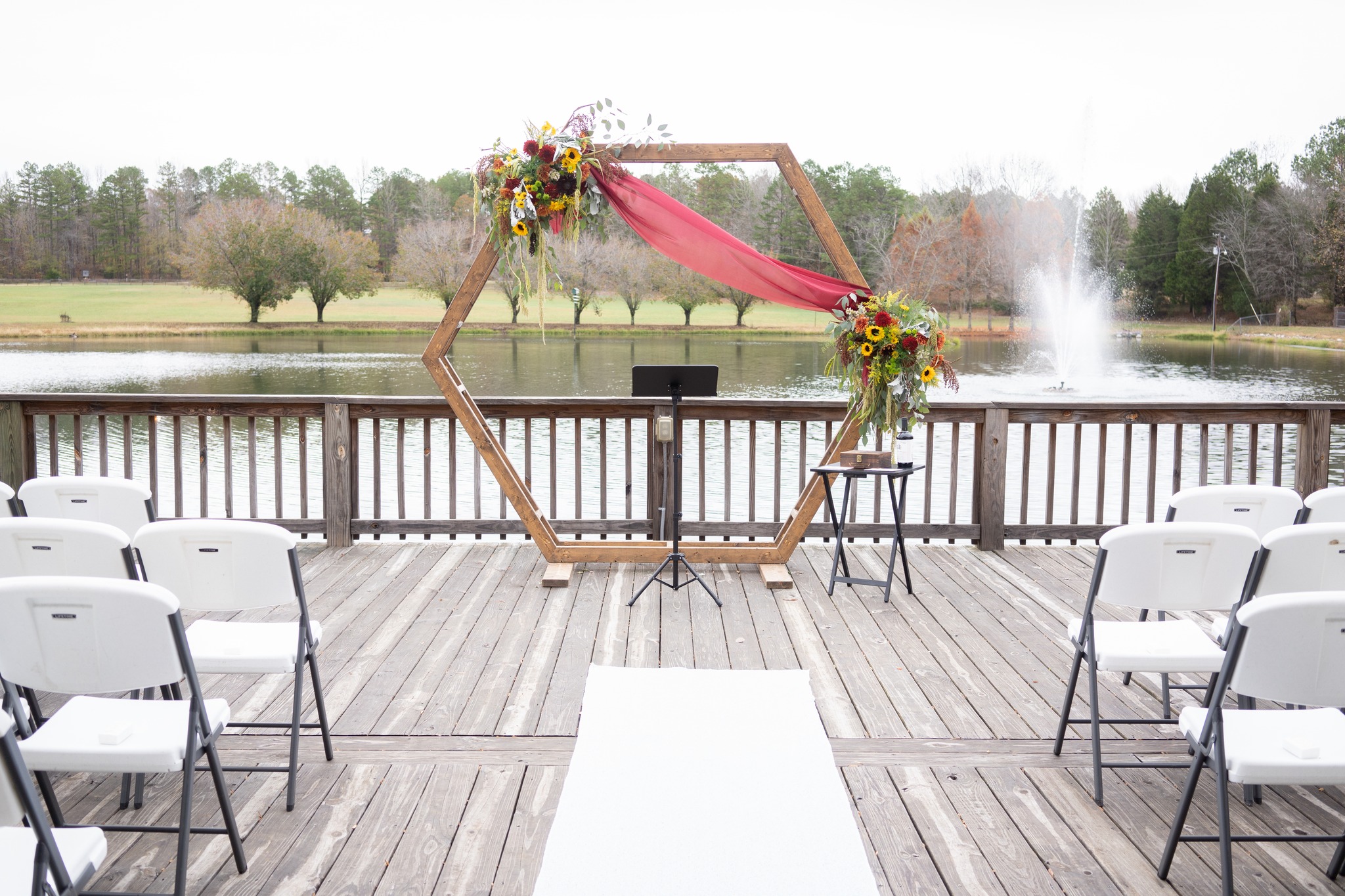 aisle leading to wedding arch with red and yellow bouquets