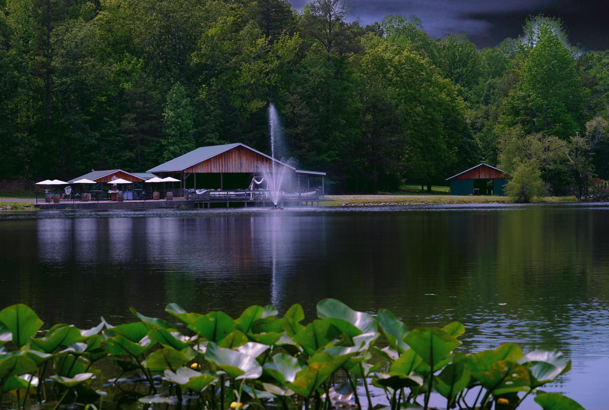fountain in the middle of lake outside wedding pavilion