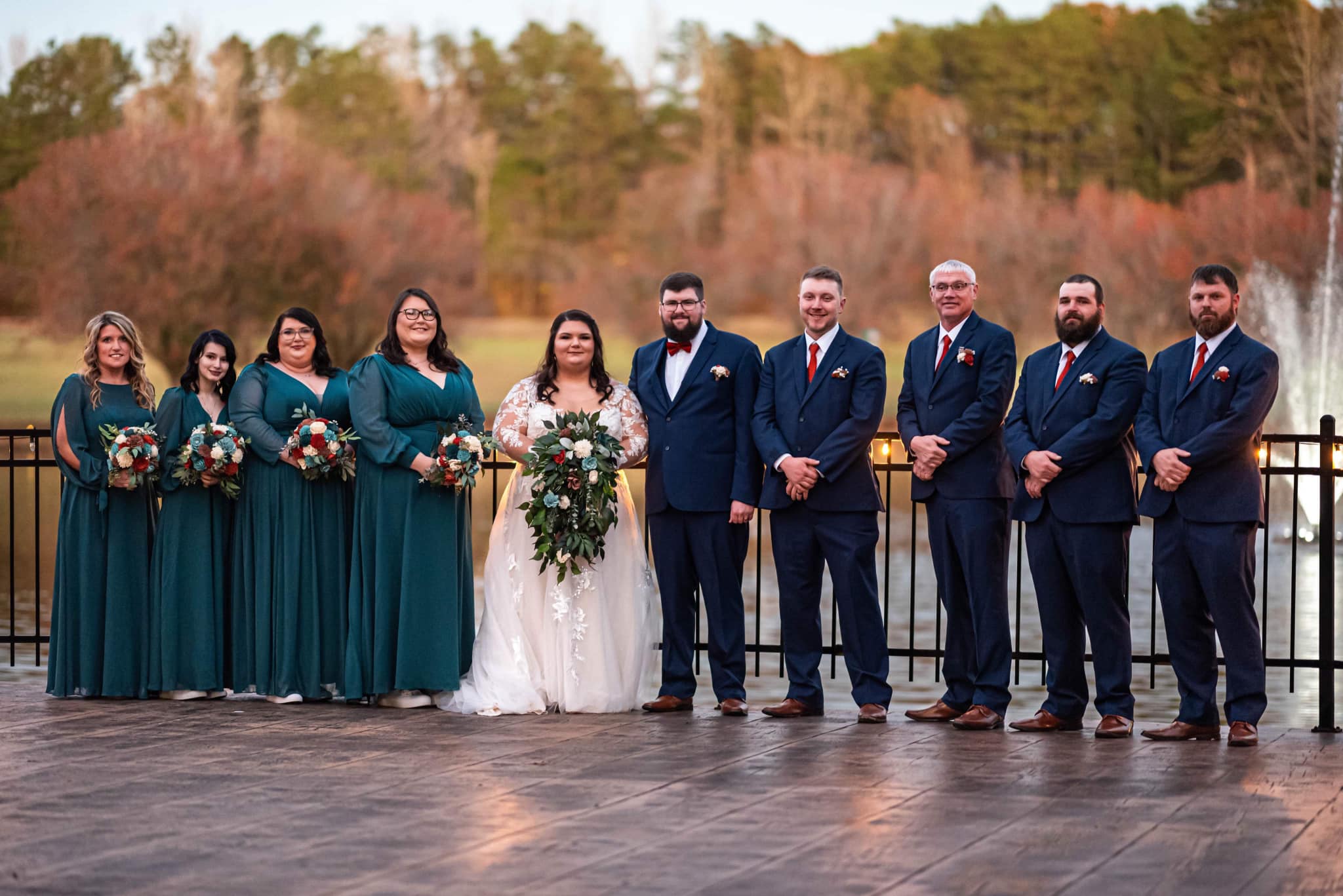 bride and groom with wedding party in front of fountain