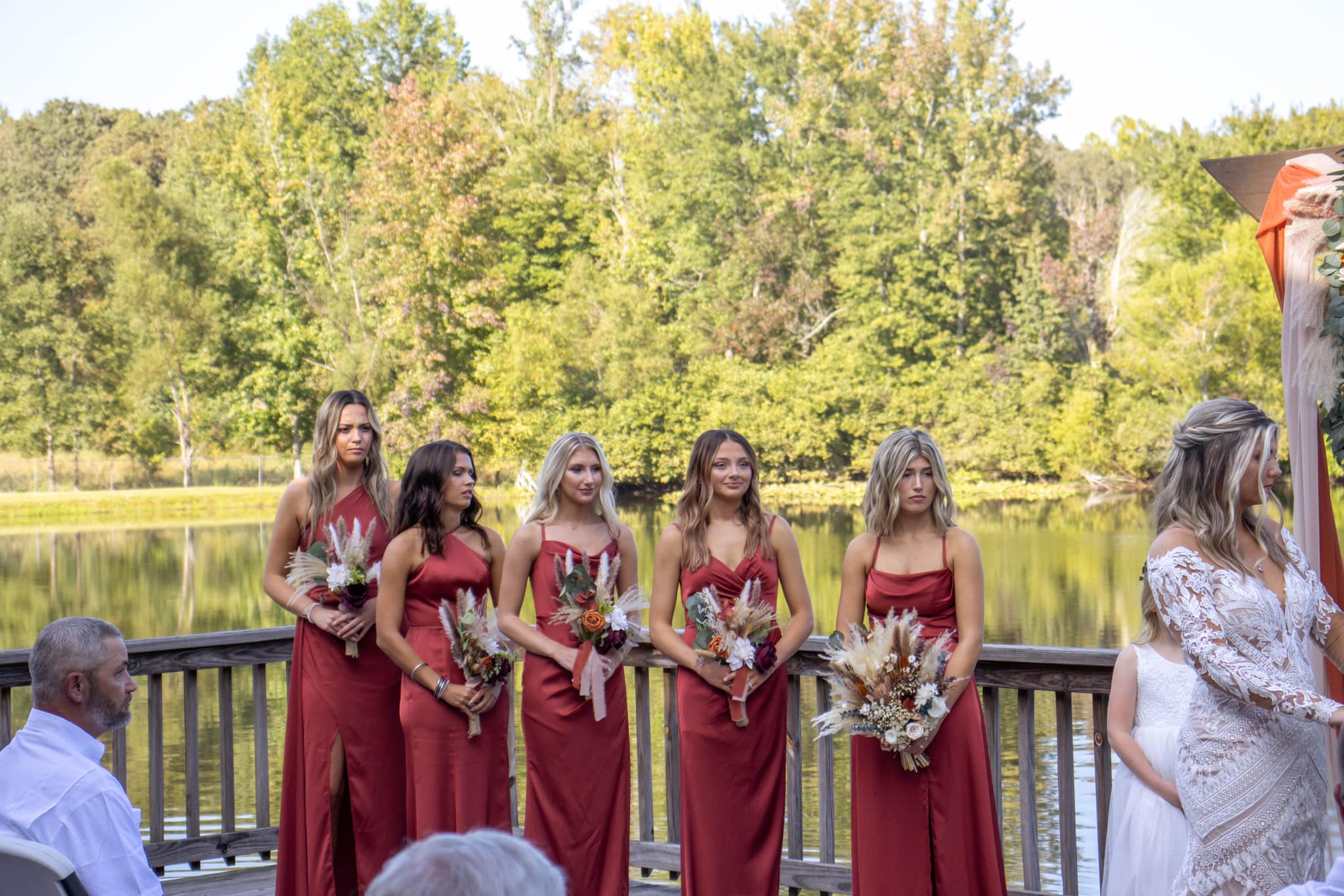 bridesmaids during ceremony in red dresses with summer bouquets