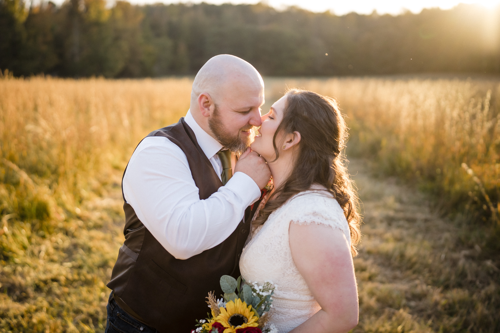 bride and groom kissing in a field