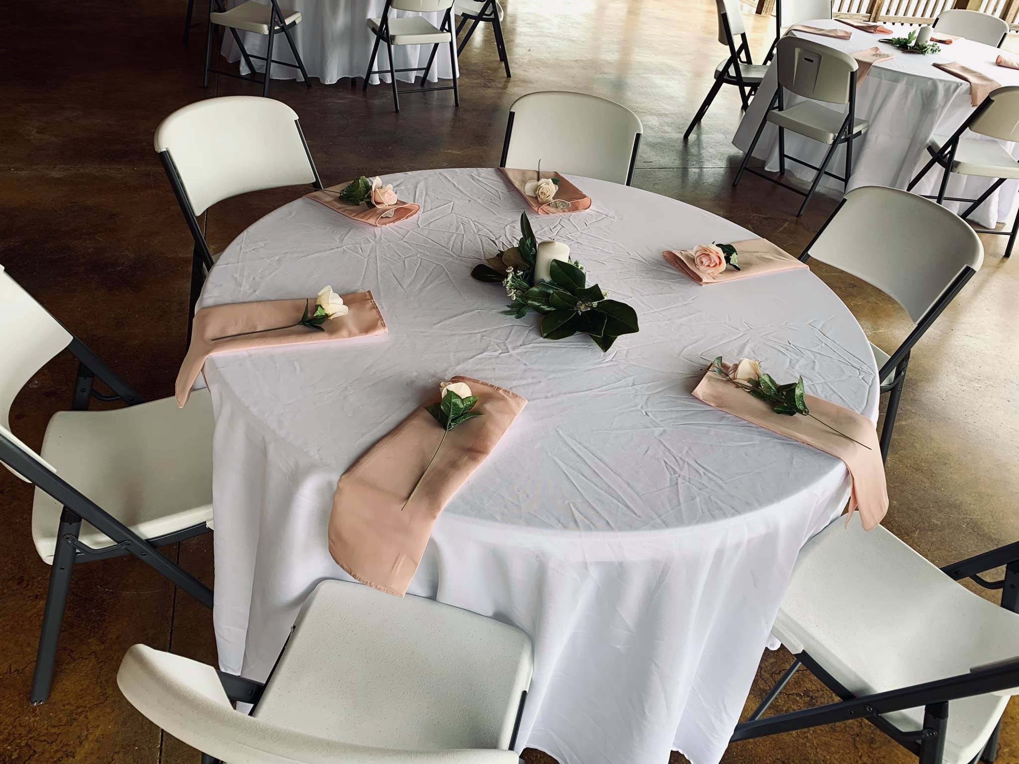 reception table with light pink cloths and white roses